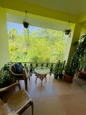 a room with a balcony with a table and plants at Whitelily's Amrithasthanam in Madikeri