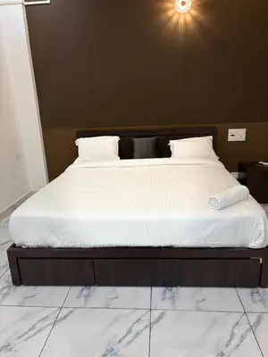 a bed with white sheets and a light above it at Zeekka Tourist Home in Meenangadi