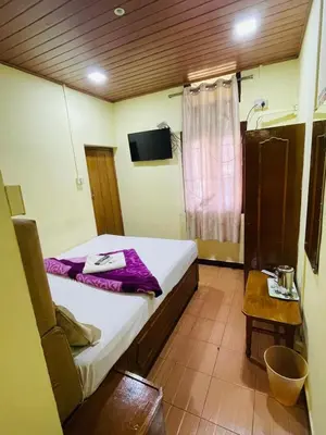 a bedroom with a bed with purple sheets and a table at budget stay-mystique inn in Ooty