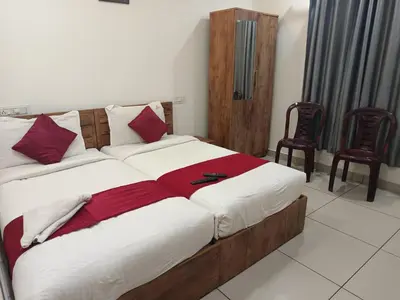 a bedroom with a large bed with two chairs at budget stay-mystique inn in Ooty