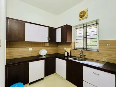 a kitchen with brown and white cabinets and a sink at Anandha Vibes STAY blessed in Guruvāyūr