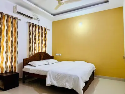 a bedroom with a bed and a yellow wall at Anandha Vibes STAY blessed in Guruvāyūr