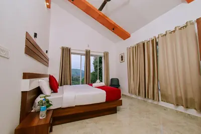 a bedroom with a bed and a large window at Alora villas in Wayanad