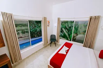 a bedroom with a bed and two large windows at Alora villas in Wayanad