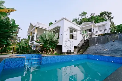 a villa with a swimming pool in front of a house at Alora villas in Wayanad