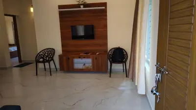 a living room with two chairs and a television at Alora villas in Wayanad