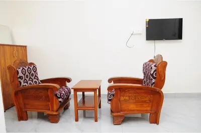 three chairs and a table in a room with a tv at Kitty Royal Inn in Ooty