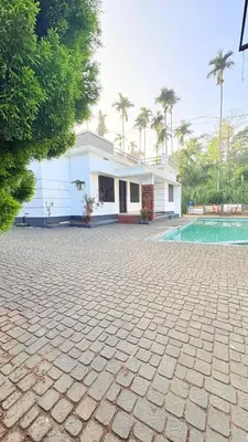 a white house with a courtyard and a pool at Grand Glorious Resort in Padinjarathara