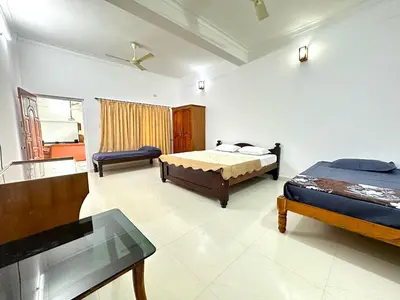 a bedroom with two beds and a tv in it at The 77 Estate Stay in Suntikoppa