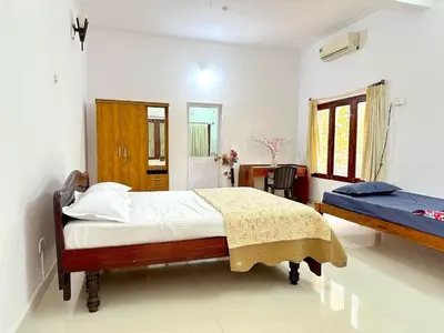 a bedroom with two beds and a table in it at The 77 Estate Stay in Suntikoppa