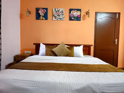 a bedroom with a large bed and some pictures on the wall at Kalon Elpis Villa in Ooty