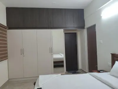 a bedroom with a bed with white cabinets and a mirror at Amaira Studio living - Coimbatore in Coimbatore