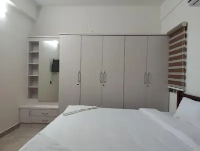 a bedroom with white cabinets and a white bed at Amaira Studio living - Coimbatore in Coimbatore