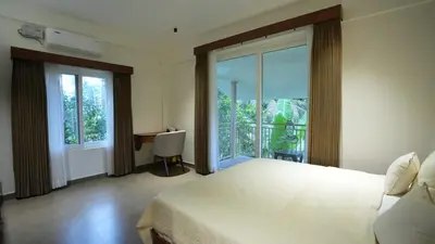 a bedroom with a large bed and a balcony at Mizuki Homestay in Trichūr