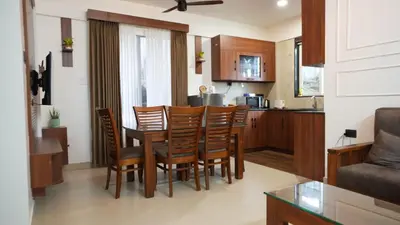 a kitchen and living room with a table and chairs at Mizuki Homestay in Trichūr