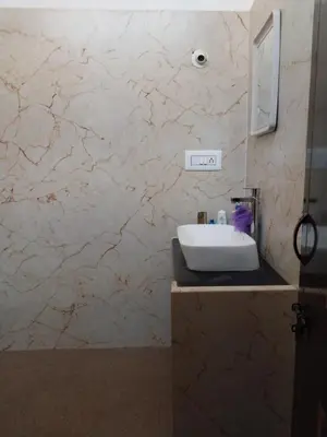 a bathroom with a sink and a marble wall at Nalee Farm Stay in Hunsūr
