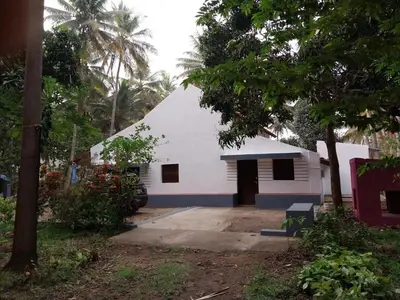 a white building with a garage in a yard at Nalee Farm Stay in Hunsūr
