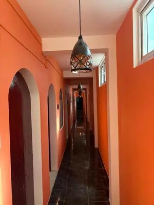 an empty hallway with orange walls and a hanging light at The Hill Bunk Heights Ooty in Ooty