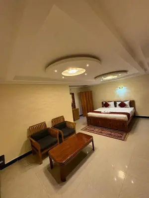 a bedroom with a bed and two chairs and a table at The Hill Bunk Heights Ooty in Ooty