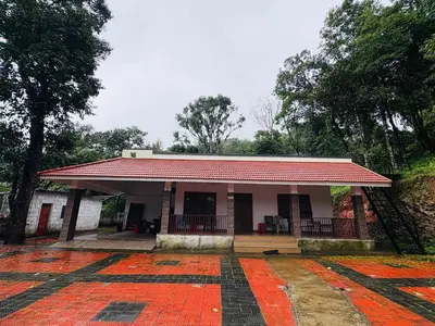 a small building with a red roof on a road at sireesha estate cottage stay in Madikeri