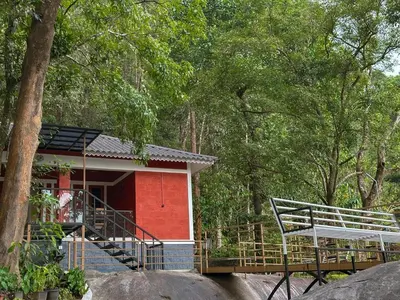a small red house with a staircase in the woods at Rockview in Kalpetta
