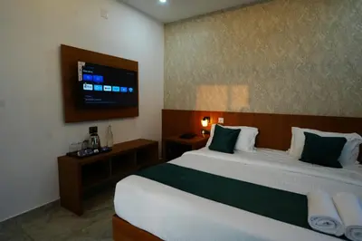 a bedroom with two beds and a tv on the wall at Palm Wave Beach Resort in Cherai Beach
