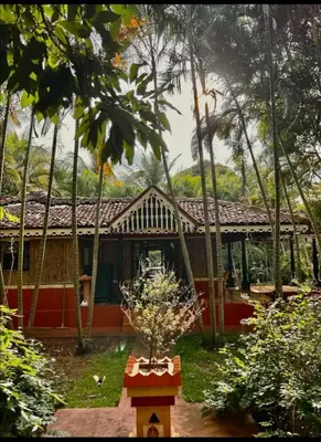 a house in the middle of a yard with trees at NATUREs LAP FARM STAY Mysore in Mysore