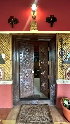 an entrance to a room with a large wooden door at NATUREs LAP FARM STAY Mysore in Mysore