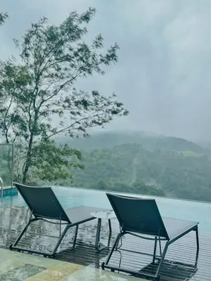 two chairs and a table next to the water at Vythiri Waves Resort l 3BR Private Pool Villa in Vayittiri