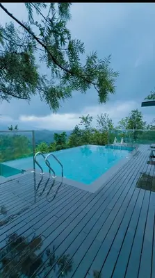 a large swimming pool on a wooden deck at Vythiri Waves Resort l 3BR Private Pool Villa in Vayittiri