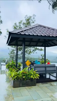 a bench under an umbrella on a patio at Vythiri Waves Resort l 3BR Private Pool Villa in Vayittiri