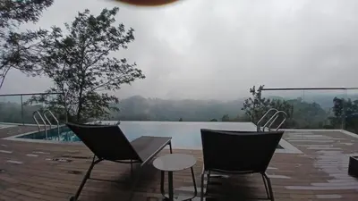two chairs and a table on a deck with a pool at Vythiri Waves Resort l 3BR Private Pool Villa in Vayittiri