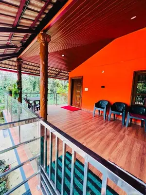 a porch with two chairs and an orange wall at Aiyappa Stayz in Madikeri