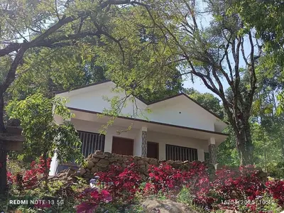 a small white house with flowers in front of it at Amber Mount Resorts in Kanthalloor