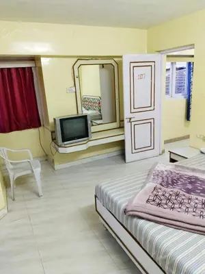 a hotel room with a bed and a television at BKC Lakshmi Cottage in Ooty
