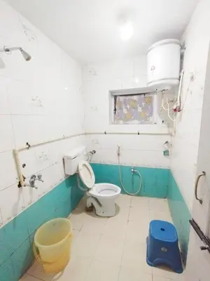 a bathroom with a toilet and a window and a bucket at BKC Lakshmi Cottage in Ooty