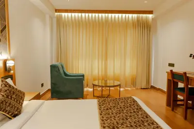 a bedroom with a bed and a chair and a table at Hotel Sky International in Kizhake Chālakudi
