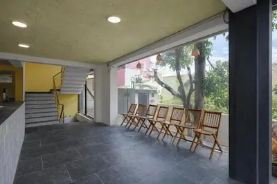 a group of chairs sitting on a porch with windows at Rooms By DeVerveil in Mysore