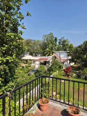 a balcony with potted plants and houses in the background at Prabhu Villla Upper Deck in Perumbavoor