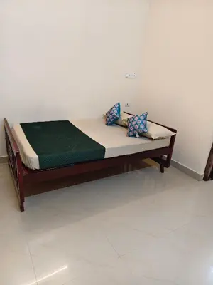 a wooden bed in a room with a green mattress at Sree manjulal Inn in Guruvāyūr