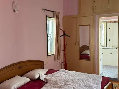 a bedroom with a bed and a door to a kitchen at Didan Stays in Coimbatore