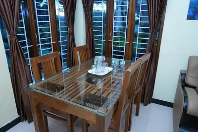 a dining room table with chairs and a glass top at Sparrow valley in Coonoor