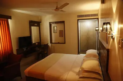 a bedroom with a bed and a desk and a television at HOTEL GRAND PLAZzA in Coimbatore