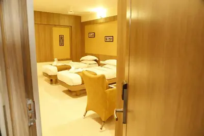 a hotel room with two beds and a chair at HOTEL GRAND PLAZzA in Coimbatore