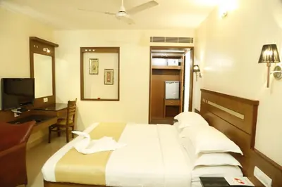 a bedroom with a bed and a desk and a television at HOTEL GRAND PLAZzA in Coimbatore