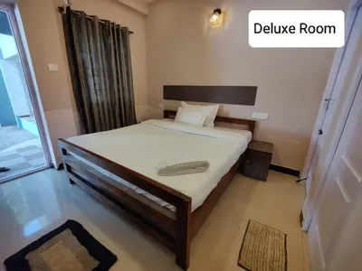 a bedroom with a bed with white sheets and a delivery room at Posh Holidays in Ooty