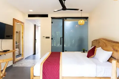 a bedroom with a large bed and a desk at Coconest Premium Deluxe Rooms in Pollāchi