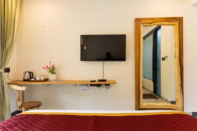a bedroom with a mirror and a tv and a bed at Coconest Premium Deluxe Rooms in Pollāchi