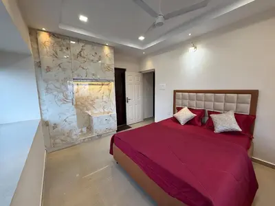 a bedroom with a red bed and a stone wall at Dwaraka-Serene Riverfront 2BHK in Palakkad