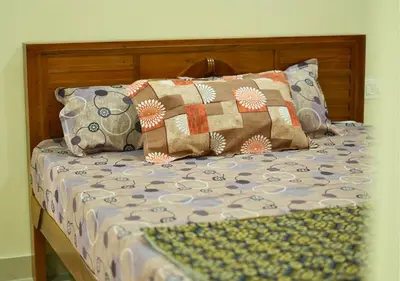 a bed with a wooden headboard with pillows at Village Homestays By Adrta Groups in Marudhamalai